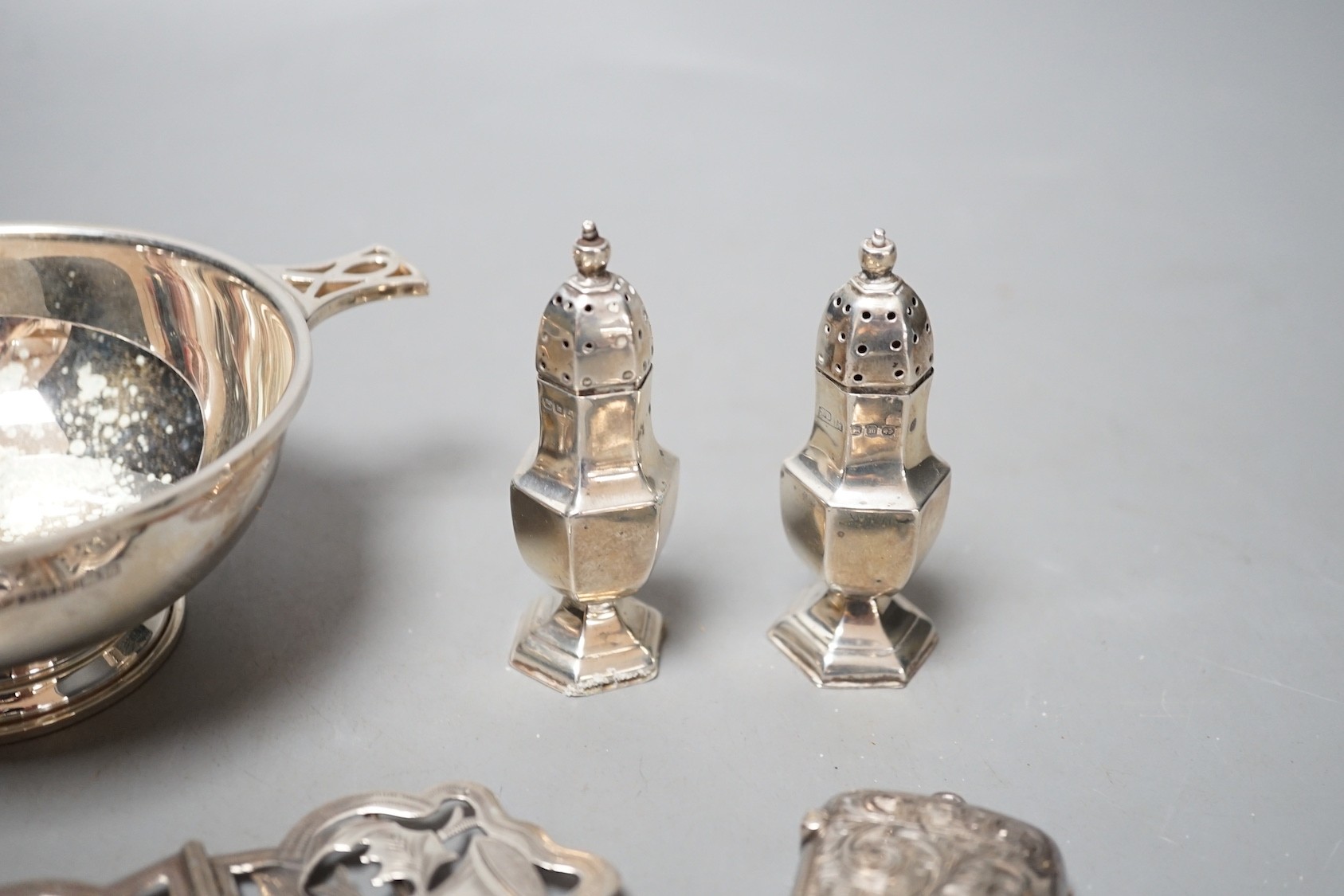 A group of assorted small silver, including a modern two handled bowl, pepperettes, vest case, belt buckle and tongs.